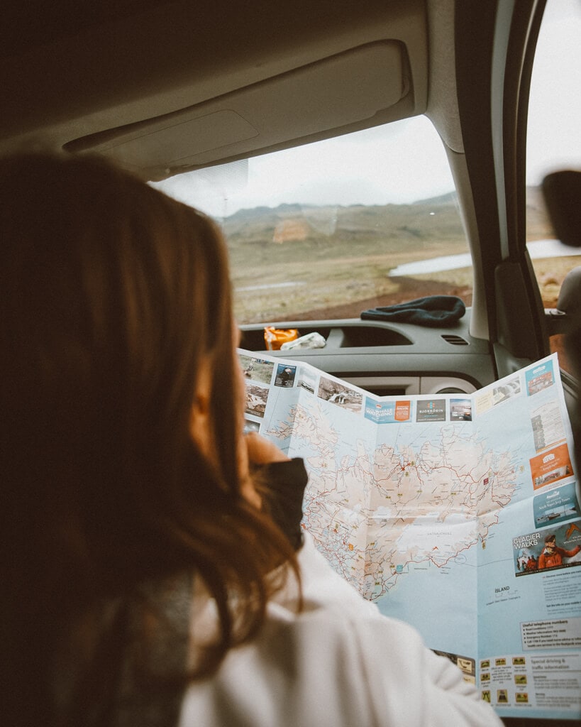 female traveler reading a map in iceland inside a camper van
