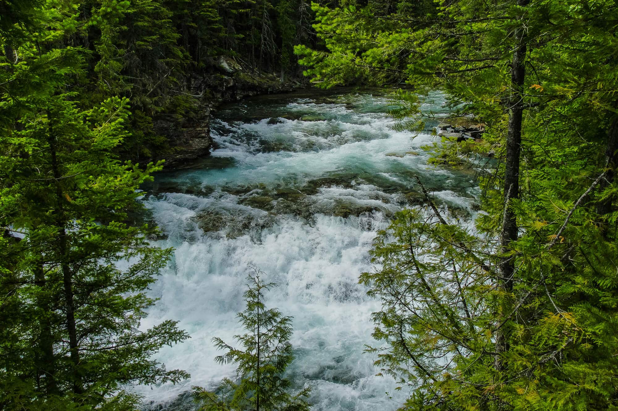 blue water rushing over mcdonald falls in glacier national park
