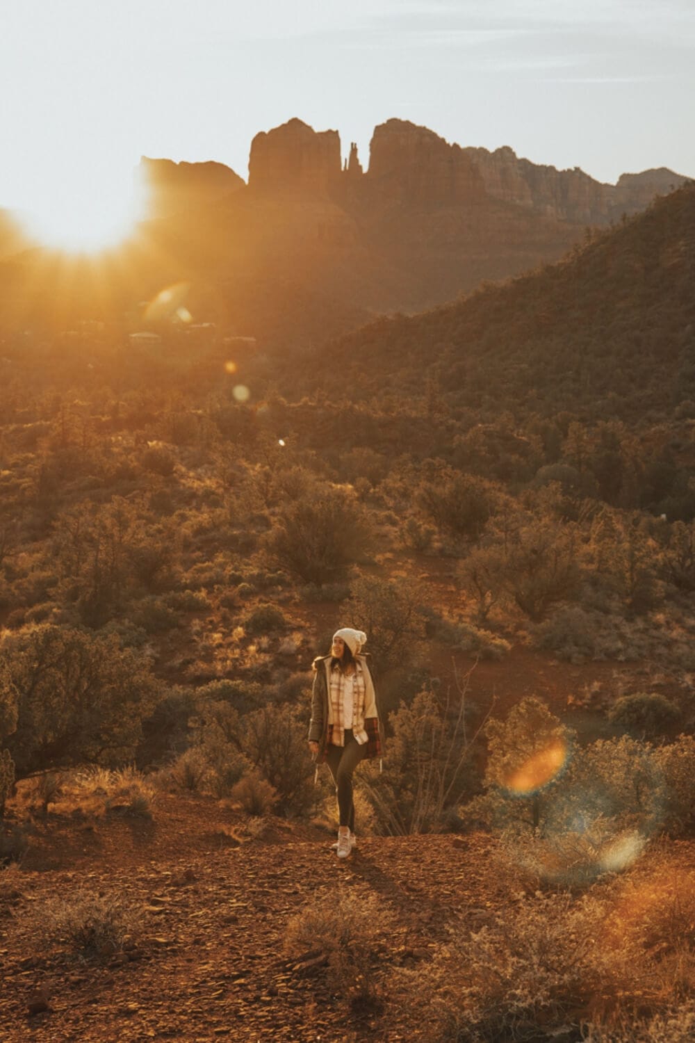 female wearing a white beanie looking out at the sunset from lover's knoll sedona arizona
