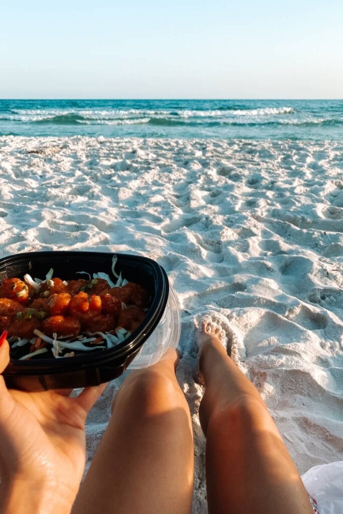 girl sitting on the beach in florida eating food