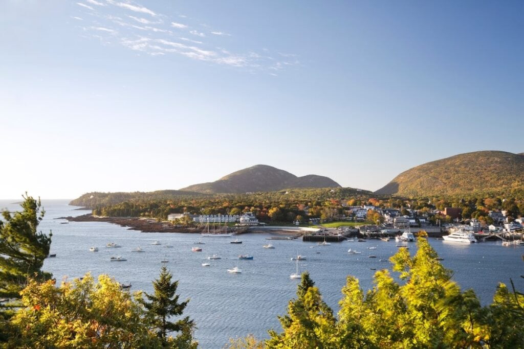 clear blue skies shinning over the hills along one of the most beautiful beach towns in the united states bar harbor maine