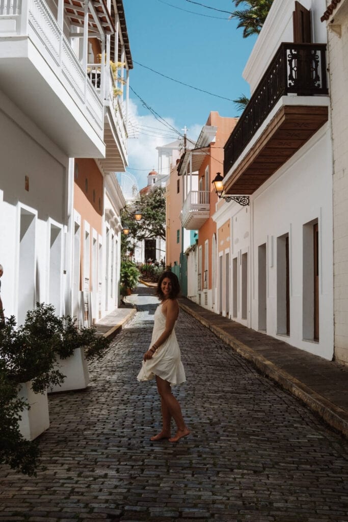 girl in a white dress standing on calle las monjas in old san juan