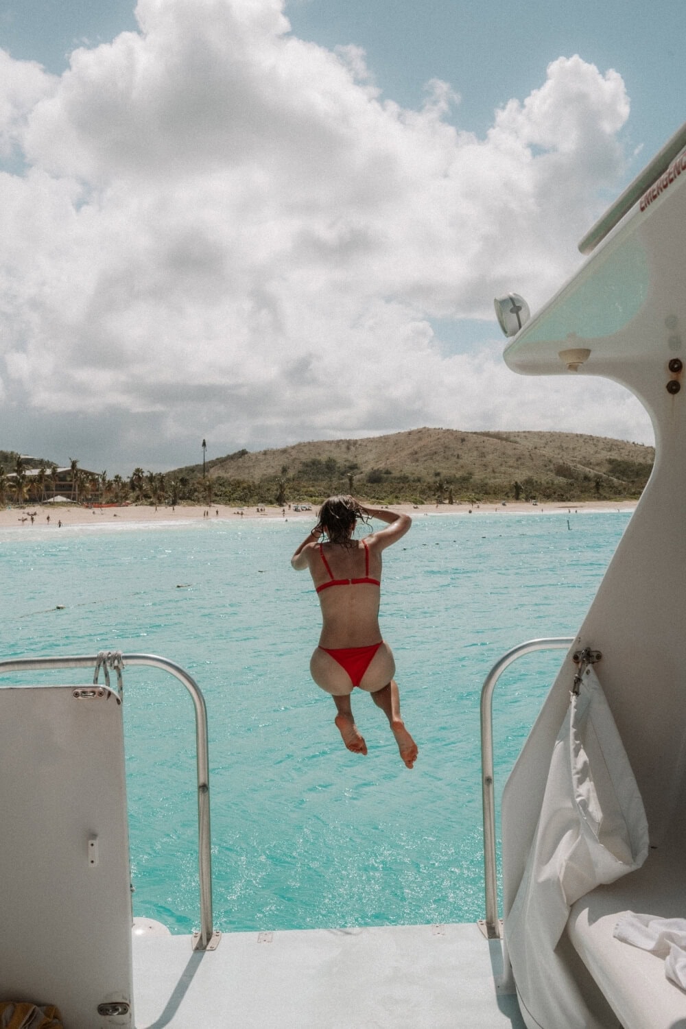 girl in a red bikini jumping off a boat to flamenco beach culebra